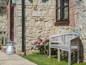 A stone building with a bench and flowers in front. - 2 Bed in Godshill (oc-ic149) (Godshill)
