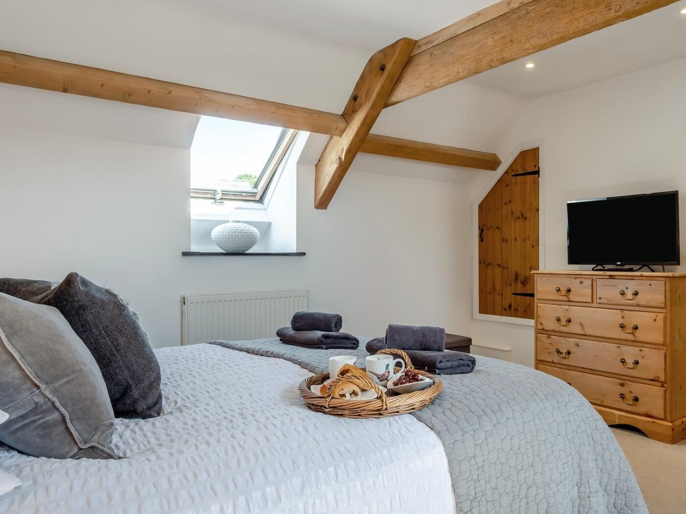 Ein Schlafzimmer mit einem Bett, einem hölzernen Schminktisch, einem Fernseher und einem Fenster.