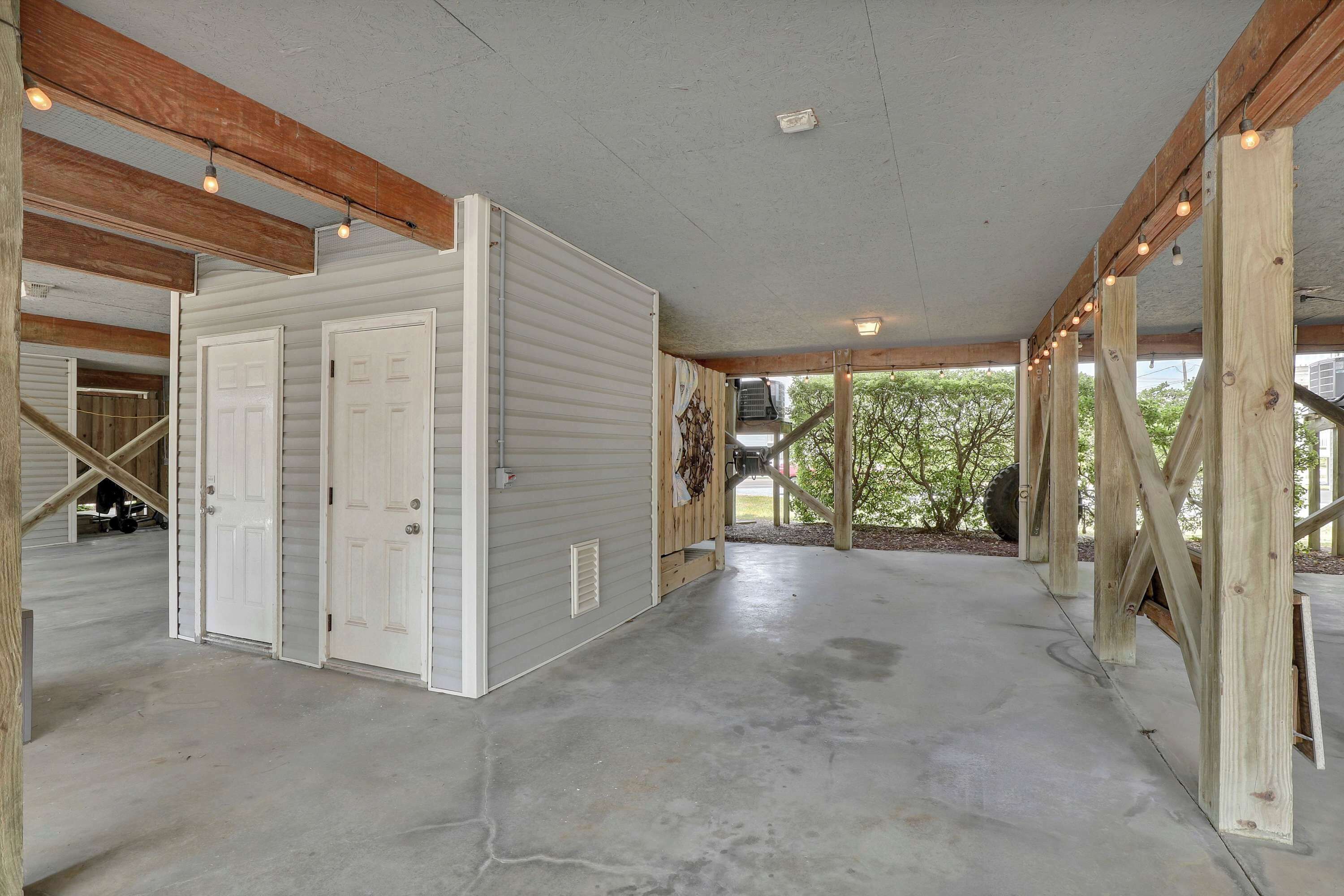 A spacious indoor area with a concrete floor, wooden beams, and a large white door.