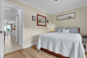 A bedroom with a bed, a nightstand, a lamp, a mirror, and a door leading to a bathroom. - Lazy Day Lookout - New Listing (Surf City)