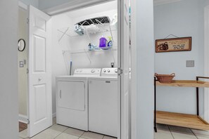 A laundry area with a washing machine, dryer, and drying rack with detergent bottles. - Lazy Day Lookout - New Listing (Surf City)