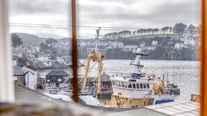 Un pueblo costero con un barco amarrado, una grúa y casas al fondo.