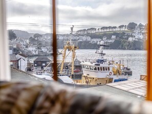 Eine Küstenstadt mit einem vertäuten Schiff, einem Kran und Häusern im Hintergrund.