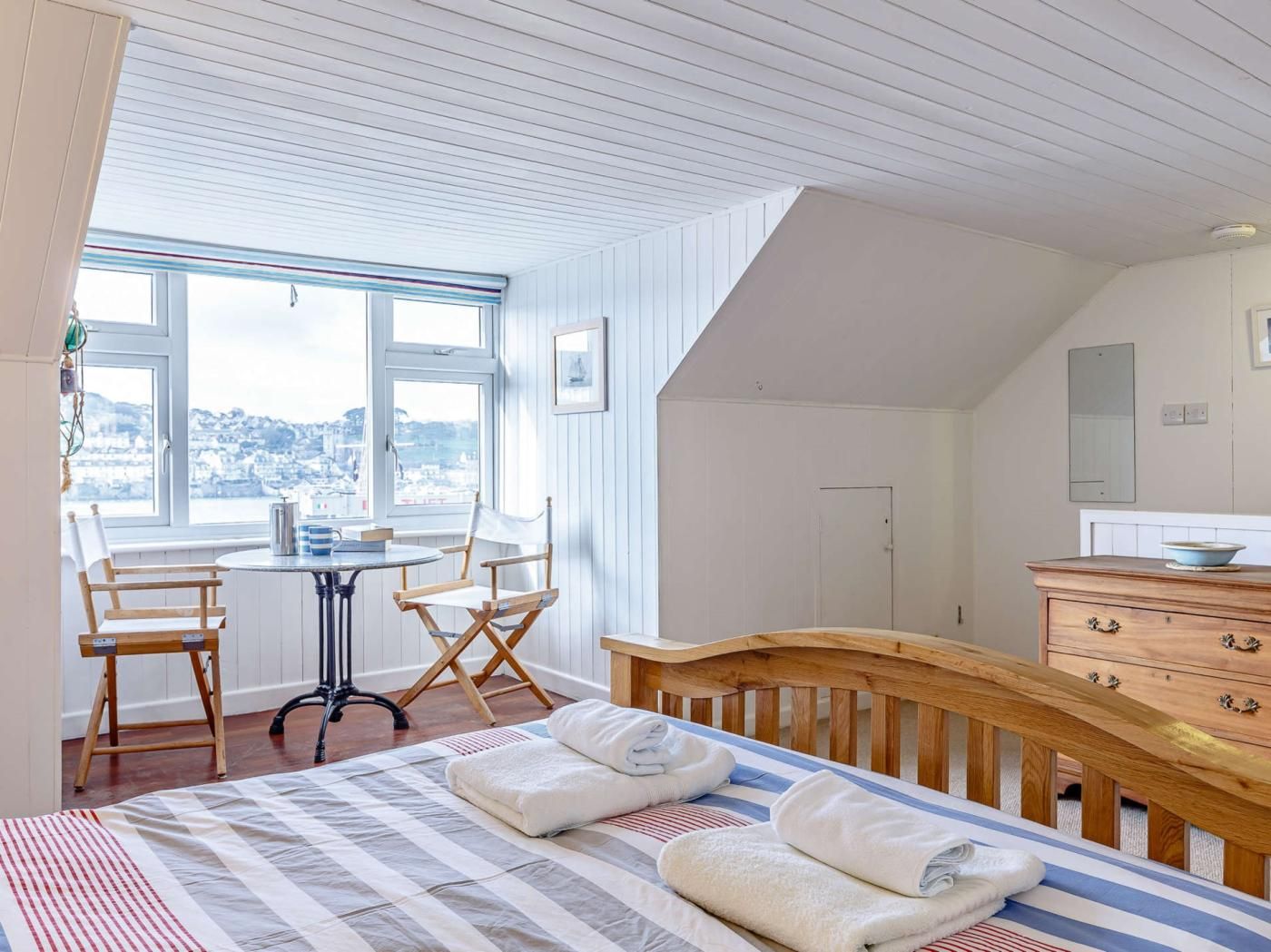 A bedroom with a bed, a desk, a chair, a dresser, and a window with a view.