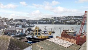 Un puerto con barcos, una grúa y edificios a lo largo de la costa.
