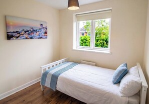 Ein Schlafzimmer mit einem Einzelbett, einem Fenster mit Blick auf Grünflächen und einem Bild an der Wand.