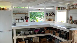 A kitchen with white cabinets, a wooden dining table, and a view of greenery outside. - To complete (Cul-de-Sac)