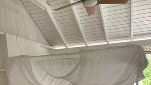 A white four-poster bed with a canopy, a ceiling fan, and a window with a view of greenery. - To complete (Cul-de-Sac)