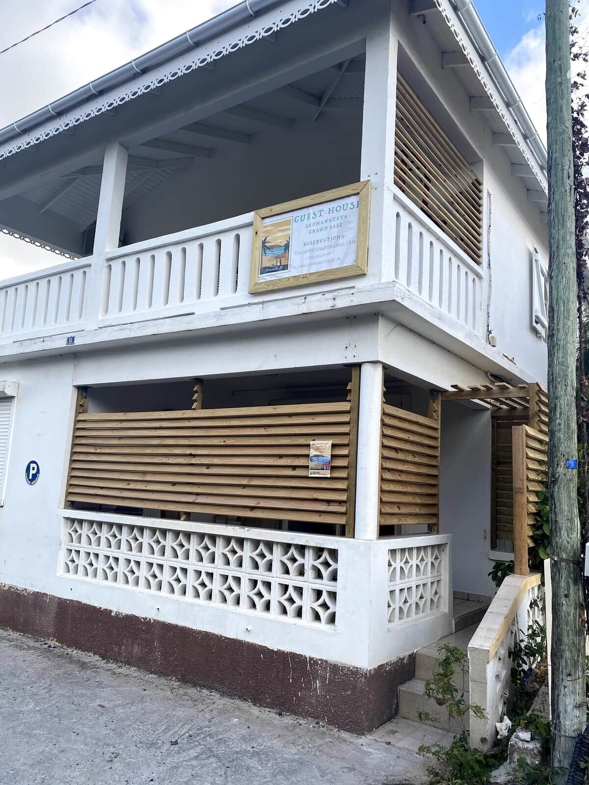 Un edificio de dos pisos con un balcón, un letrero que indica que es una casa de huéspedes y una señal de estacionamiento.
