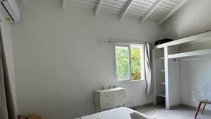 Un dormitori amb llit, armari, finestra i ventilador de sostre.
