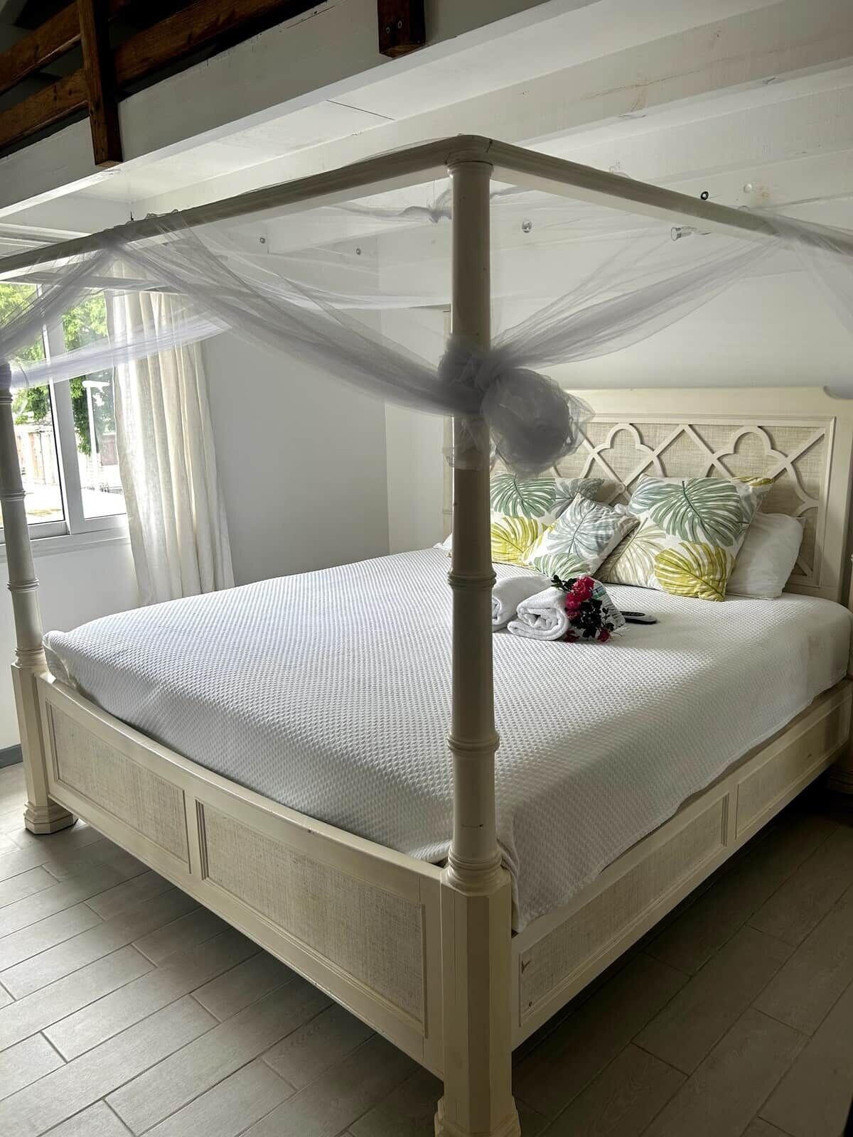 A bed with a canopy, white bedding, and a decorative headboard.