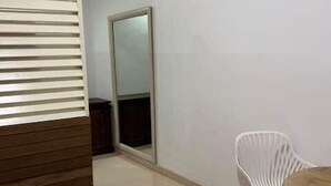 A room with a wooden bench, a white chair, a round table, and a large mirror on the wall. - Private Apartment in the Heart of Downtown Marigot (Marigot)