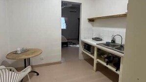 A small kitchen with a dining table and chair, a sink, and a cabinet. - Private Apartment in the Heart of Downtown Marigot (Marigot)