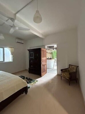 Ein Schlafzimmer mit Bett, Kleiderschrank, Sessel und Deckenventilator.