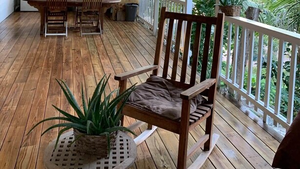 Eine Holzterrasse mit Essbereich, Küche und Topfpflanzen.