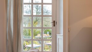Une pièce comprenant un lit, une fenêtre donnant sur du mobilier d’extérieur et une porte.