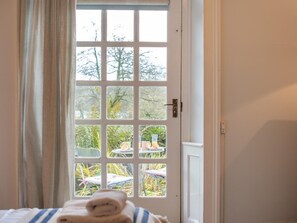 A room with a bed, a window with a view of outdoor furniture, and a door. - 3 Bed in Ambleside (oc-62587) (Claife)