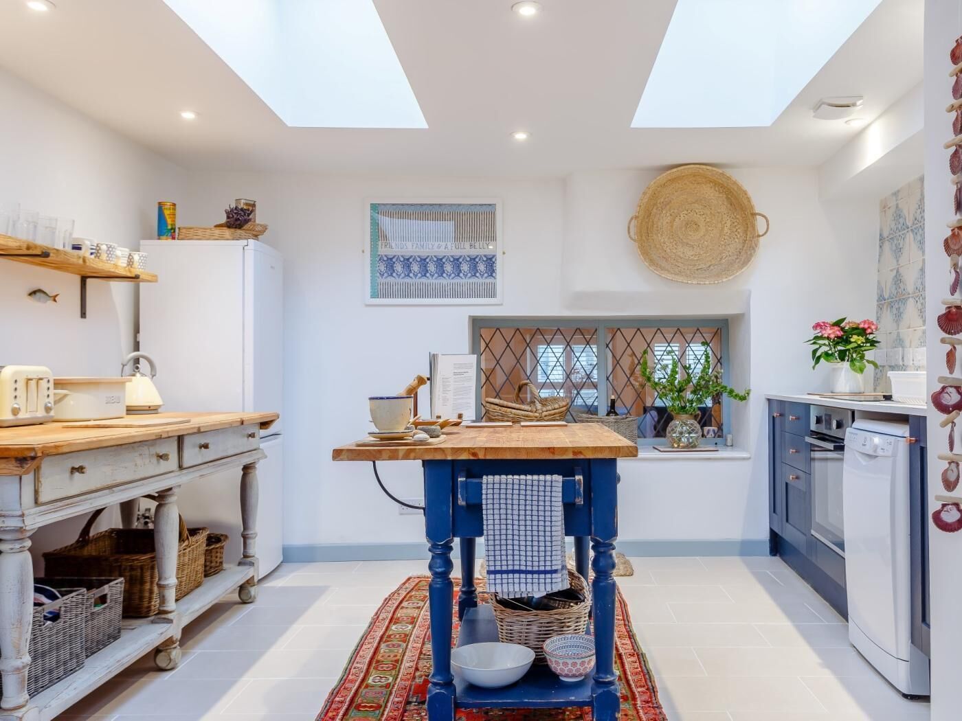 A kitchen with a skylight, wooden counter, and a blue stool.