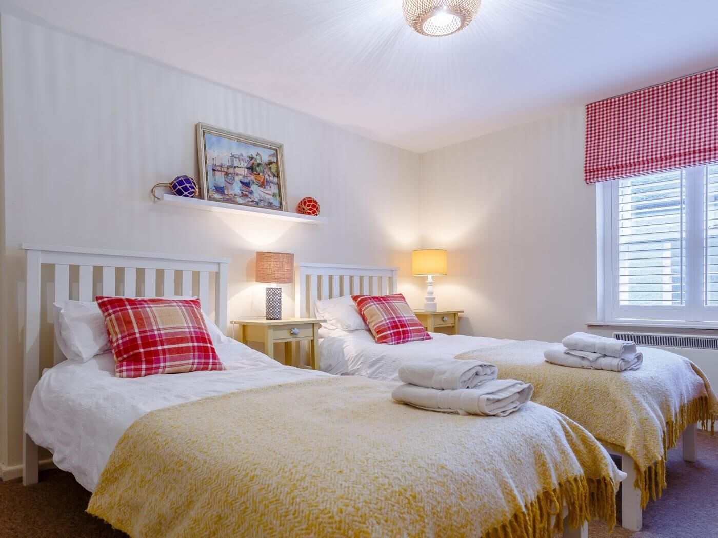 Een hotelkamer met twee bedden, wit beddengoed, een schilderij aan de muur en een raam met zonwering.