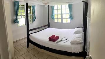 A single bed with a canopy, a window with curtains, and a door.
