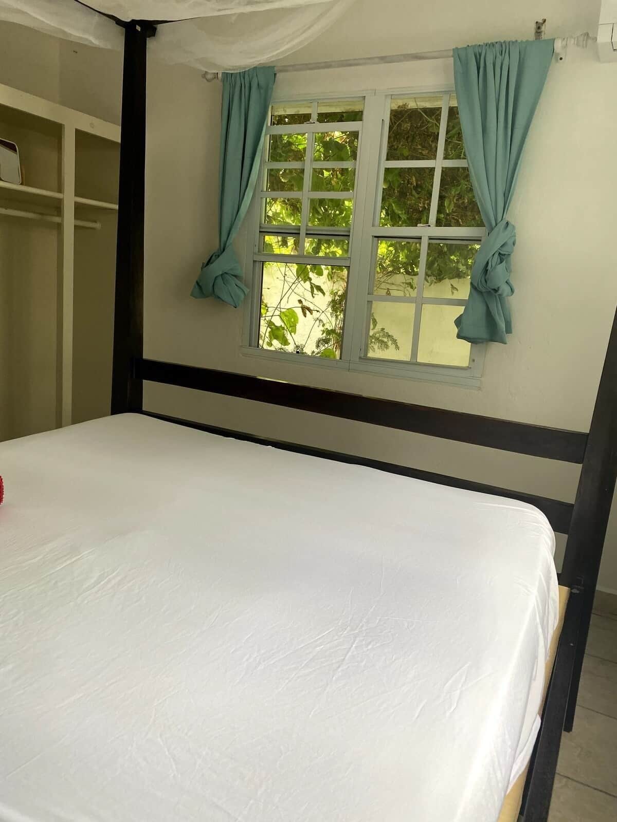 Ein Schlafzimmer mit einem Bett, einem Fenster mit Vorhängen und einem Kleiderschrank.