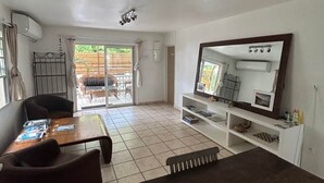 A living room with a sofa, a coffee table, a TV, and a fireplace. There is a sliding glass door leading to a patio. - Happy House in Grand Case Beach 1 (Grand Case)