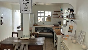 A kitchen with a sign that reads 'KEEP CALM & EAT CANDY,' a dining table with chairs, and a kitchen counter with various items. - Happy House in Grand Case Beach 1 (Grand Case)