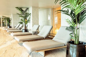A row of lounge chairs with cushions, a large potted plant, and a marble floor. - One-bedroom apartment in Bayline, Armação de Pêra, for a maximum of 2 guests. Includes AC, Wi-Fi, equipped kitchen, private parking, pool, spa and gym. Short walk to the beach and promenade. (Armação de Pêra)