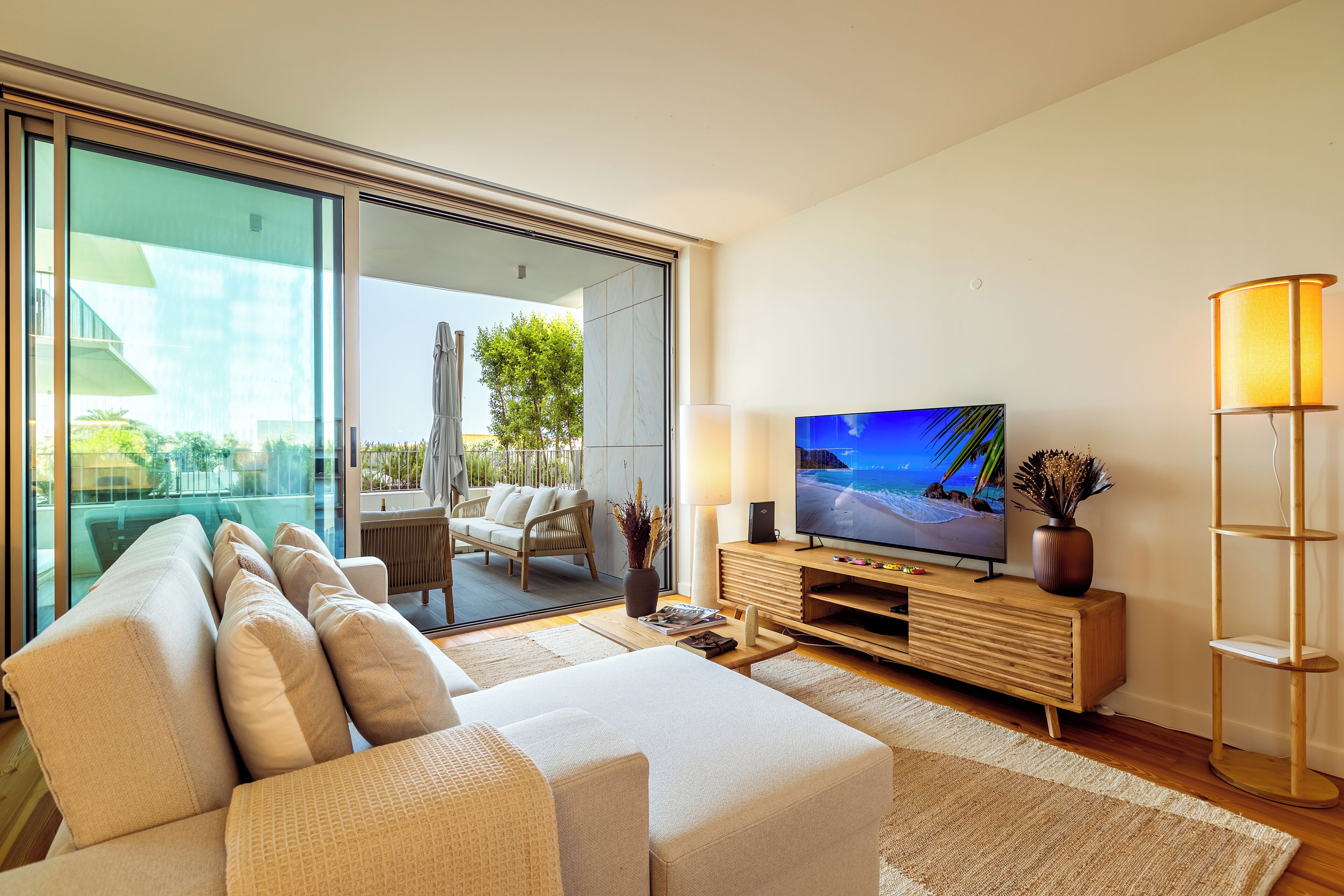 A modern living room with a sofa, TV, and a lamp.