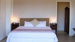 A bedroom with a bed, bedside lamps, a rug, a wall-mounted air conditioner, and a door. - Room-casa Allegria, Camera Felicità - ad (Parabita)