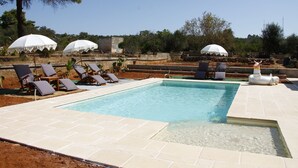 A swimming pool with lounge chairs and umbrellas, surrounded by a landscaped garden. - Room-casa Allegria, Camera Felicità - ad (Parabita)