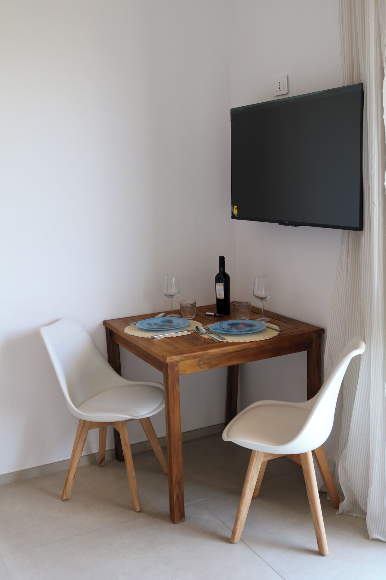 Un tavolo da pranzo con due sedie, una bottiglia di vino e due bicchieri da vino.
