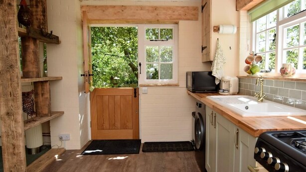 Une cuisine de taille réduite, avec une porte en bois, une fenêtre, un lave-linge et une cuisinière.