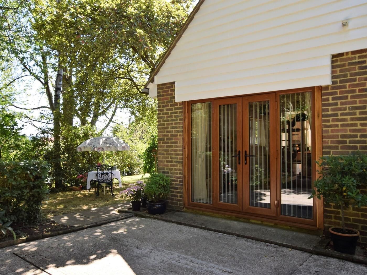 A house with a brick exterior, a sliding glass door, and a small patio area with a table and chairs.