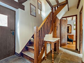 Eine Holztreppe mit einem Stuhl oben, einer Tür mit Schlüsselloch und einem Spiegel an der Wand.