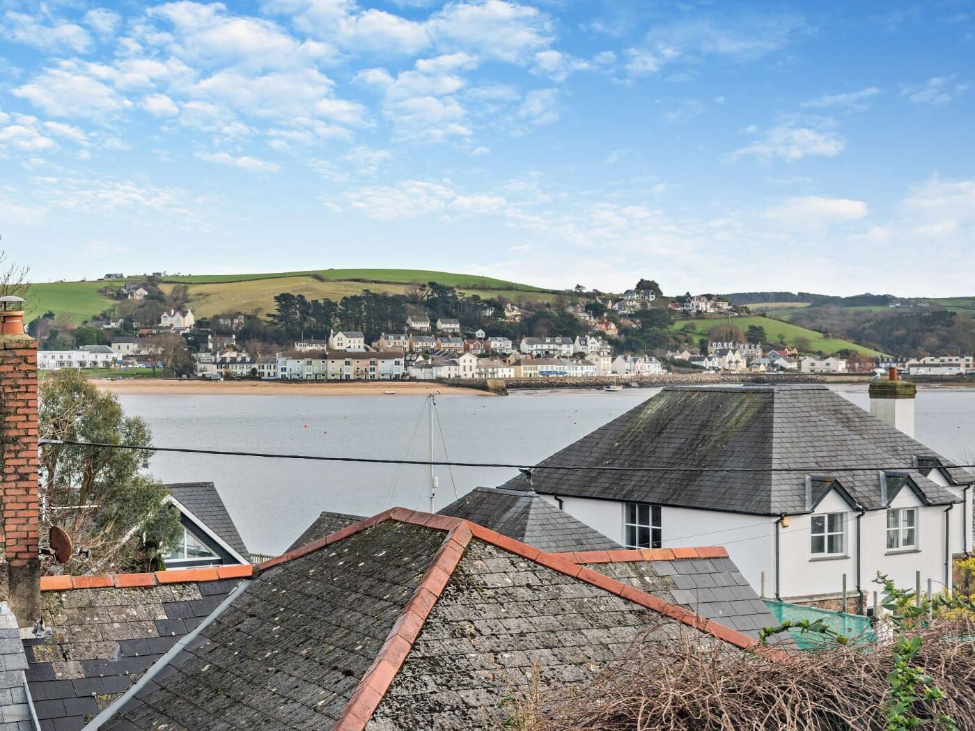 Une ville côtière offrant une vue sur la mer et sur des collines en arrière-plan.