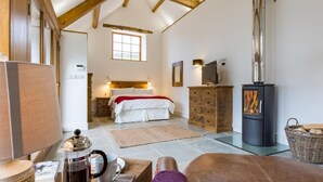 Un dormitorio acogedor con cama, cómoda y estufa de leña.