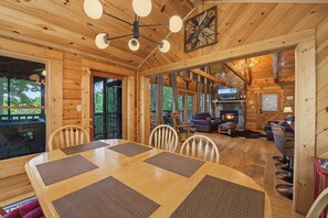 Gather around the dining table for meals while enjoying natural light and views of the surrounding greenery. The open layout connects seamlessly to the cozy living area with its stone fireplace. - Escape to Firefly Ridge in Sevierville and discover your perfect Tennessee mount (Sevierville)