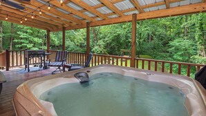 A hot tub under a wooden deck with a view of a forest. - Escape to Friendly Bear Cabin, a welcoming three-bedroom retreat in Sevierville (Sevierville)