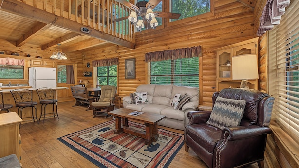 A log cabin interior with a dining area, a sofa, a leather armchair, and a ceiling fan. - Escape to Friendly Bear Cabin, a welcoming three-bedroom retreat in Sevierville (Sevierville)