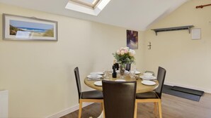 A dining room with a round table, chairs, a vase of flowers, and a skylight. - 2 Bed in Beaminster (oc-63047) (Littlewindsor)