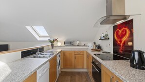 A modern kitchen with a skylight, built-in appliances, and a heart-themed artwork. - 2 Bed in Beaminster (oc-63047) (Littlewindsor)