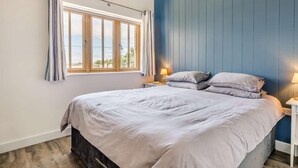 A bedroom with a bed, a window with curtains, a nightstand with a lamp, and a view of the outdoors. - 2 Bed in Bideford (oc-62964) (Appledore)