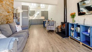 A modern living room with a sofa, a fireplace, a bookshelf, and a TV mounted on the wall. - 2 Bed in Bideford (oc-62964) (Appledore)