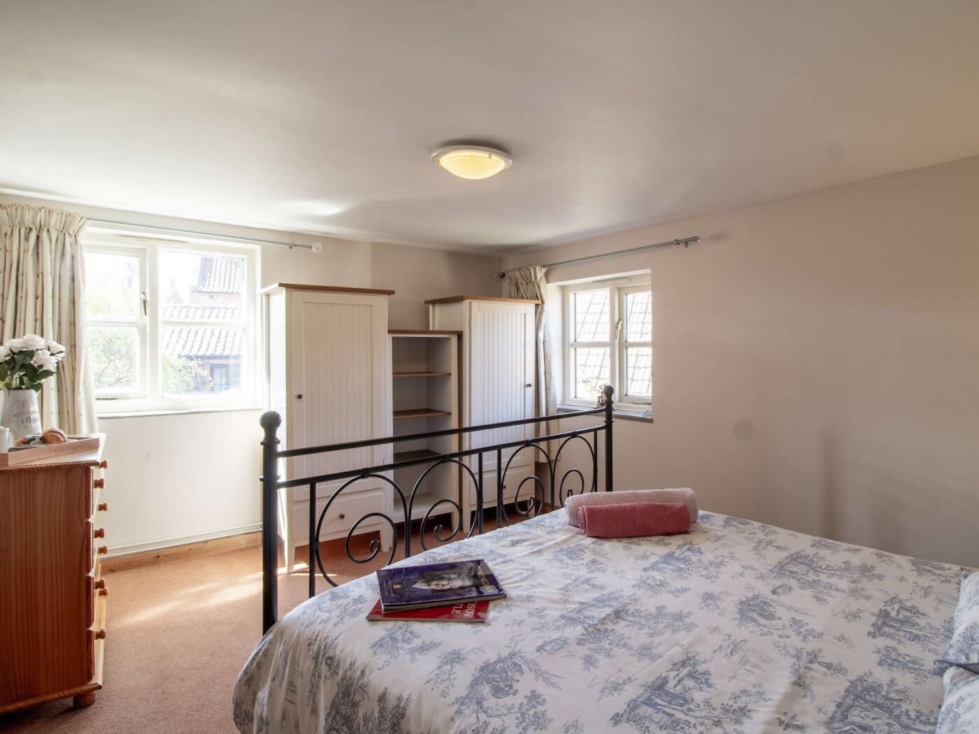 A bedroom with a bed, a dresser, a window, and a wardrobe.