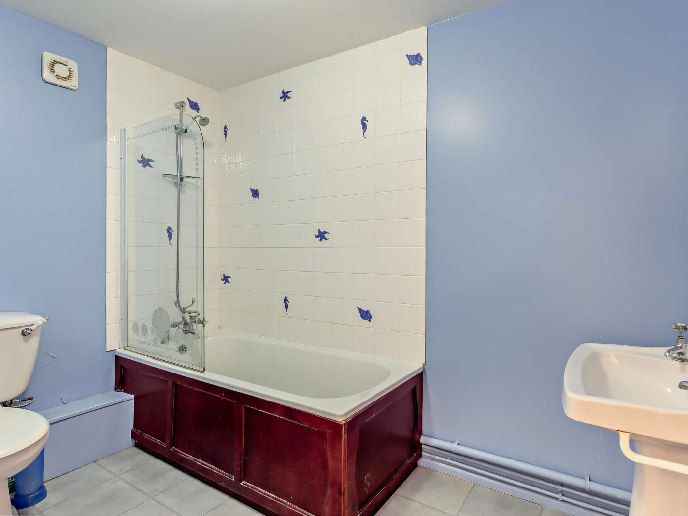 Une salle de bain avec une douche à parois de verre, une baignoire blanche, un meuble-lavabo rouge et un lavabo blanc.