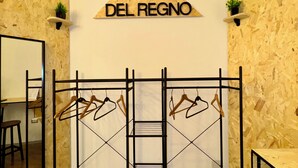 A room with a wooden wall, a metal rack with clothes, a mirror, and a sign that reads 'DEL REGNO'. - Del Regno Holiday House (Pompei)