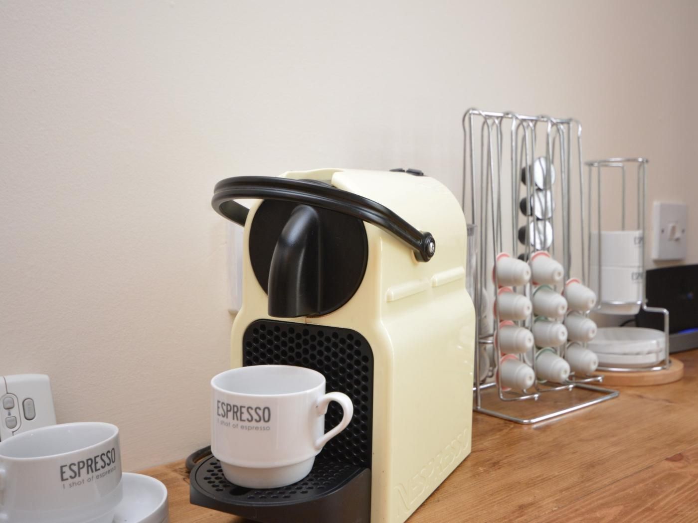 A coffee machine with a cup of espresso on a tray, a coffee machine stand, and a coffee pod holder.