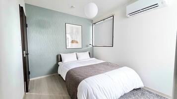 A modern bedroom with a bed, a wall-mounted air conditioner, and a ceiling light fixture.