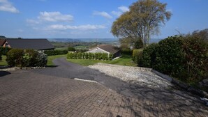 Ein ländlicher Weg führt zu einem Haus mit Kiesweg und Blick auf die Landschaft.